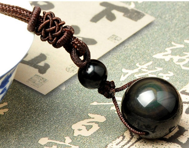 Close up of polished obsidian bead on black cord